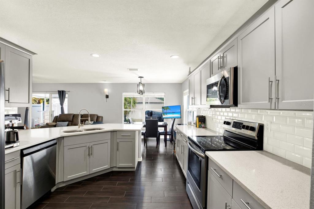 A kitchen with gray cabinets, white countertops, stainless steel appliances, and dark wood-look flooring — 11434 CRESTLAKE VILLAGE DRIVE, RIVERVIEW, FL