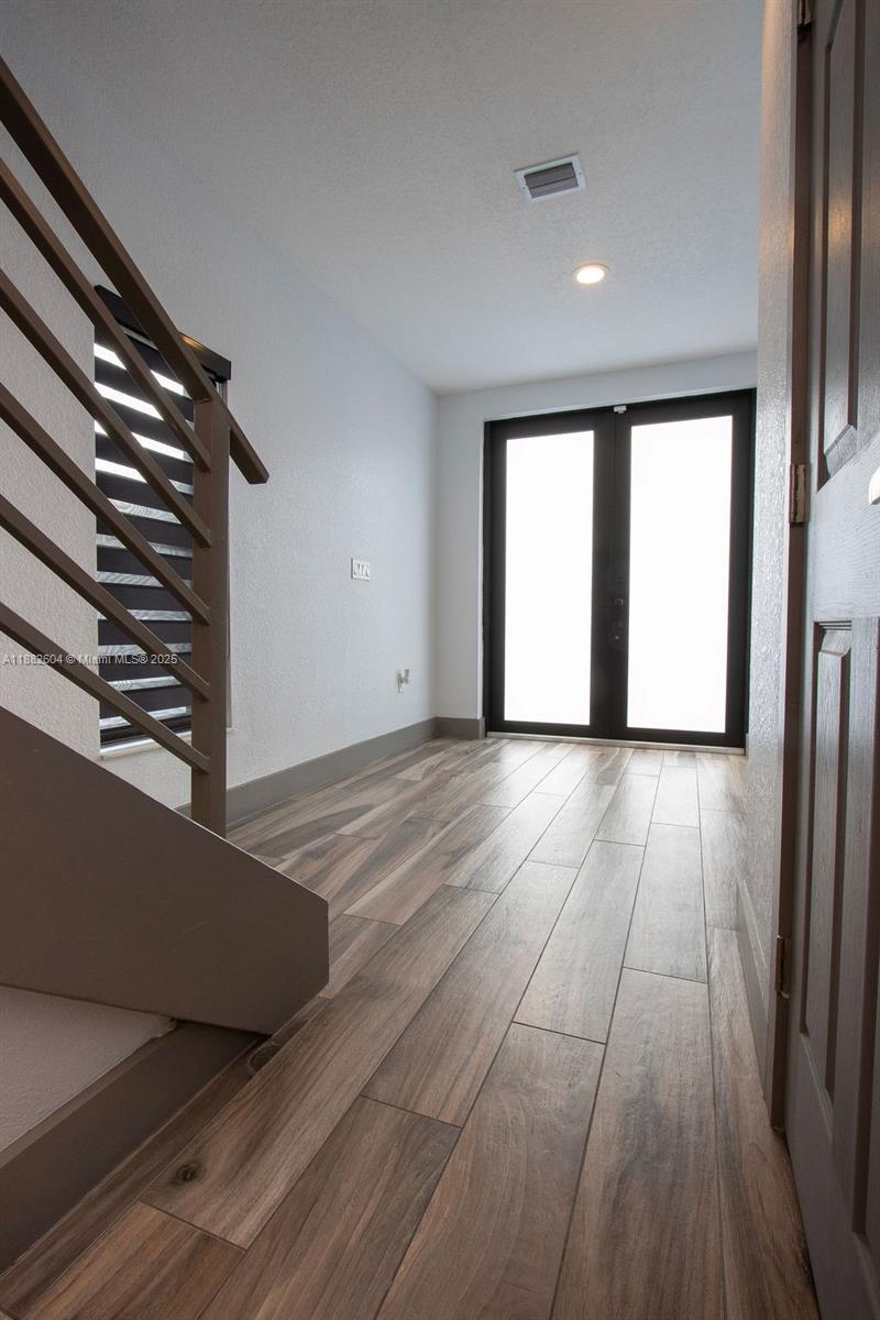 A bright entryway features wood-look tile flooring, a staircase with metal railings, and double doors — 2061 Washington Ave # 4, Opa-Locka FL 33054, OPA-LOCKA, FL