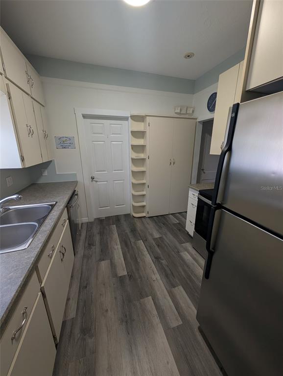 A kitchen features light-colored cabinetry, stainless steel appliances, and gray wood-look flooring — 321-B W PENNSYLVANIA AVENUE, DELAND, FL