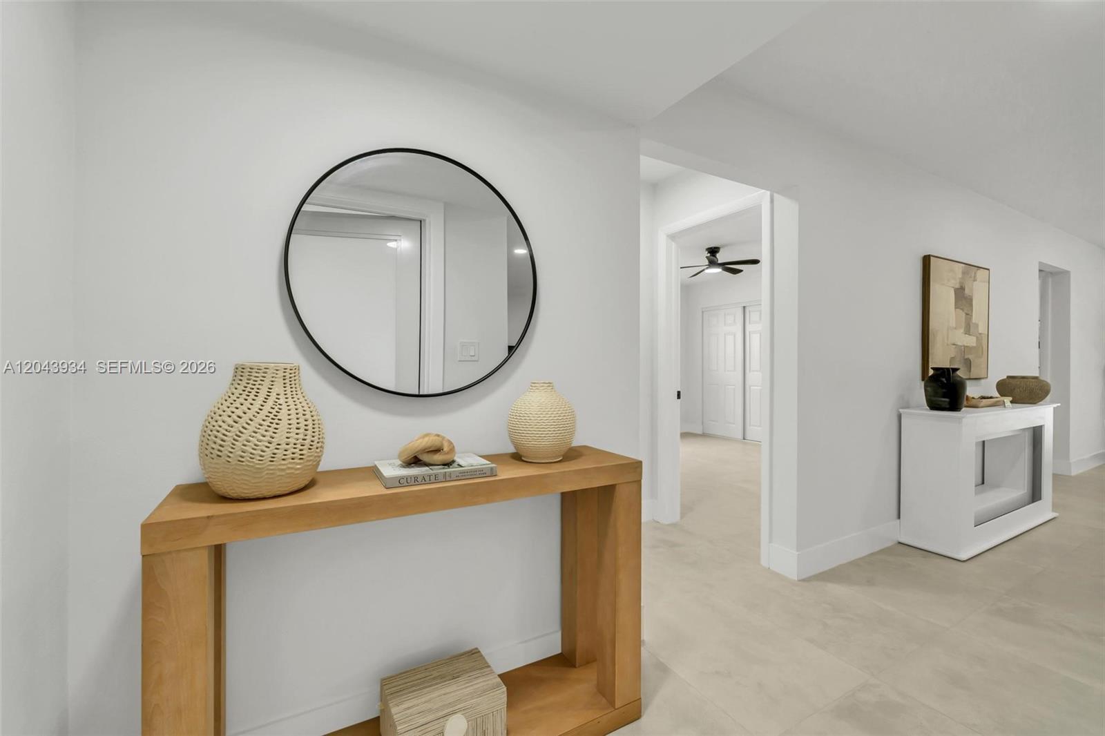 A hallway features a wooden console table with decor, a round mirror, and tile flooring — 8970 SW 53rd St, Cooper City FL 33328, COOPER CITY, FL