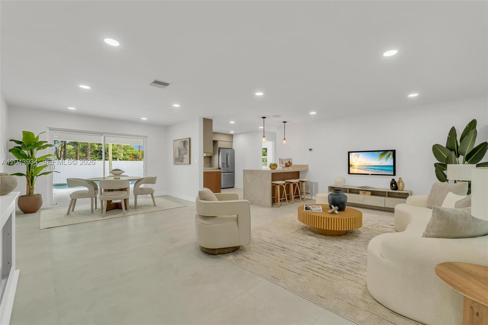 An open-concept living and dining area features light tile floors, neutral furniture, and a kitchen — 8970 SW 53rd St, Cooper City FL 33328, COOPER CITY, FL