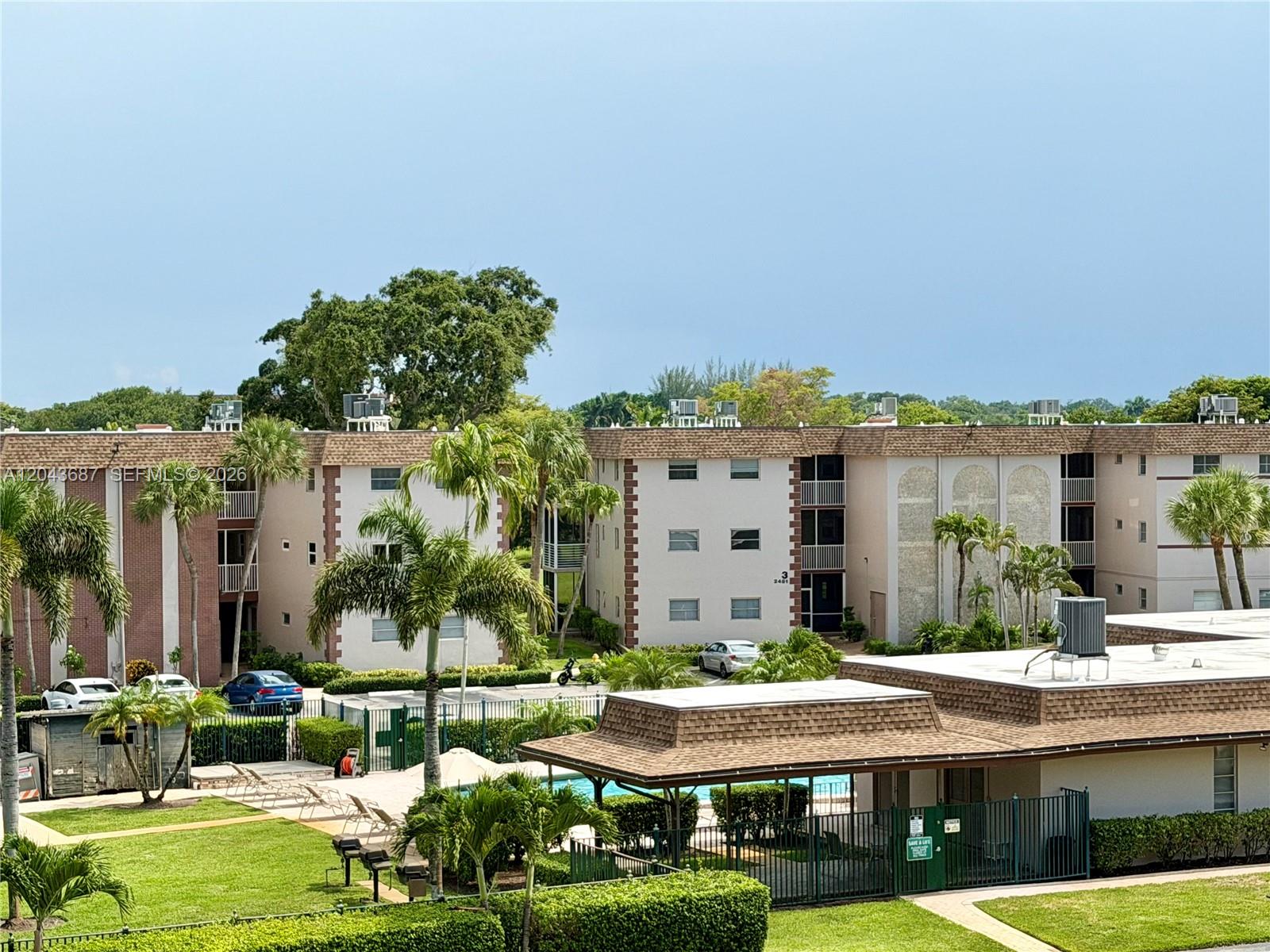 An exterior view of multi-story apartment buildings with a swimming pool and palm trees — 8101 SW 24th Ct # 405, Davie FL 33324, DAVIE, FL