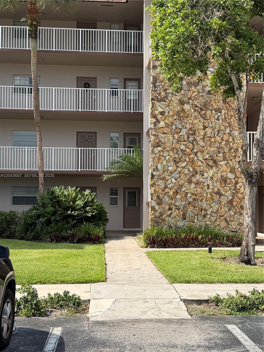A three-story apartment building exterior features white railings, brown doors, and a stone facade — 8101 SW 24th Ct # 405, Davie FL 33324, DAVIE, FL