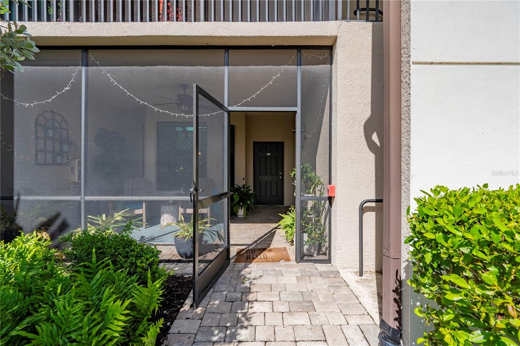 A paved walkway leads to a screened-in porch entrance with a dark front door — 5517 PALMER CIRCLE UNIT 106, BRADENTON, FL