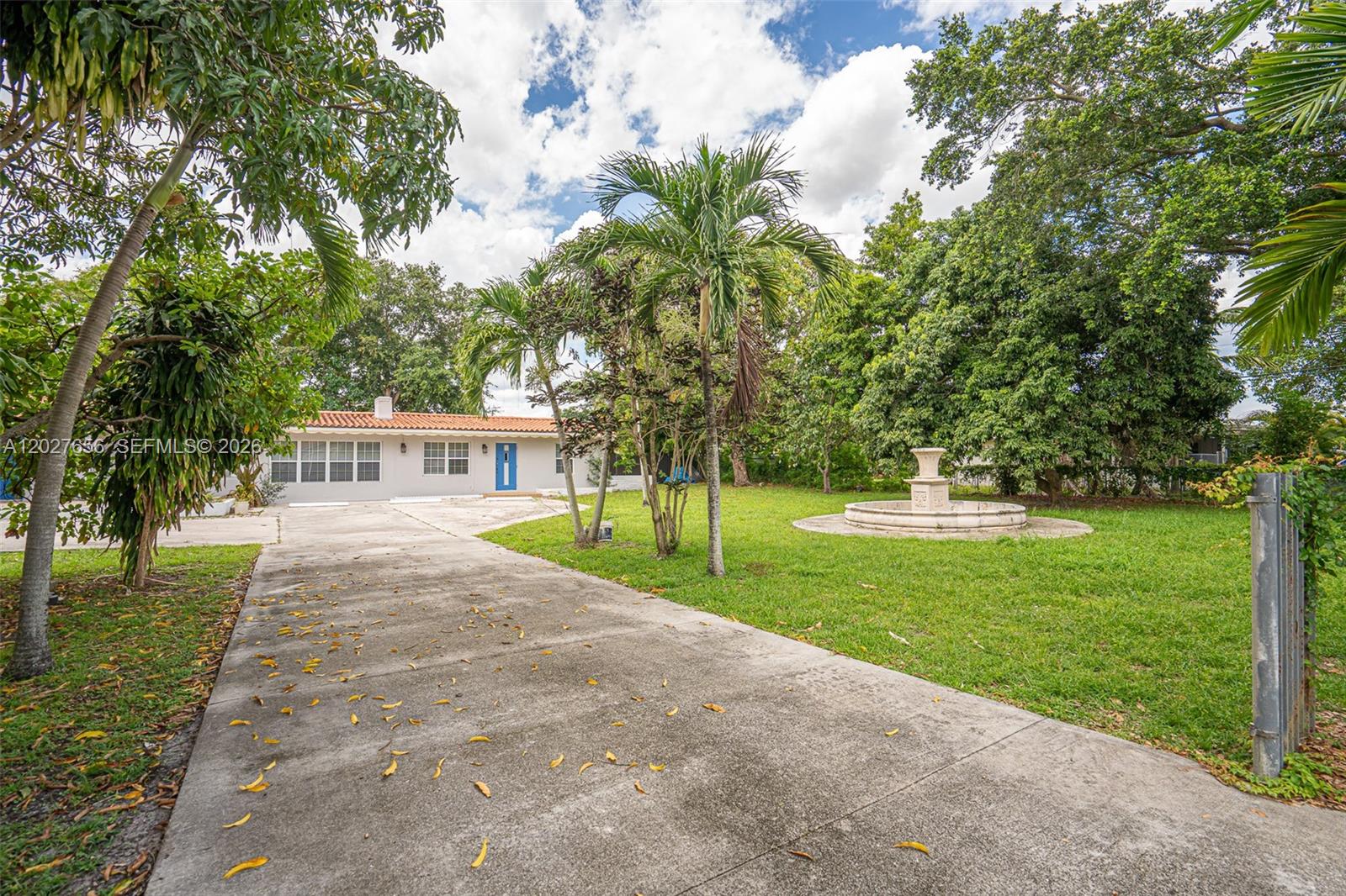 A concrete driveway leads to a single-story house with a fountain in the front yard — 5613 Pierce St # 2, Hollywood FL 33021, HOLLYWOOD, FL