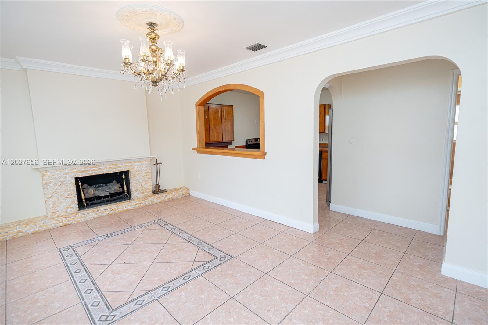 A living room features a stone fireplace, a chandelier, and an arched kitchen pass-through window — 5613 Pierce St # 2, Hollywood FL 33021, HOLLYWOOD, FL