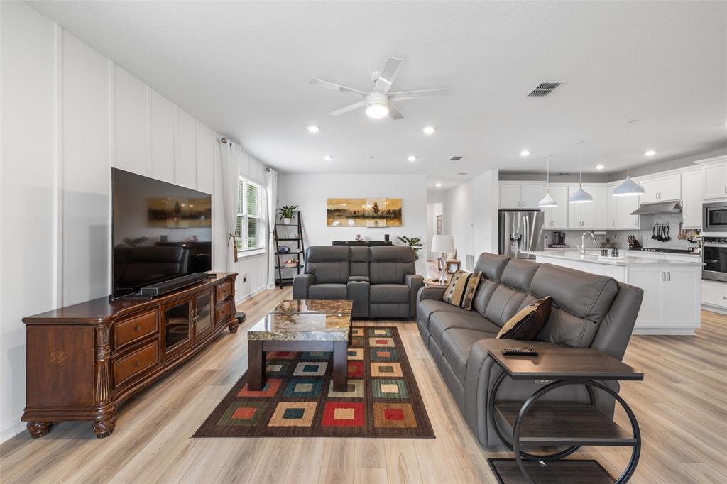 A living room with gray leather sofas, a patterned rug, and an open-concept white kitchen — 783 LITTLE CLOUD PLACE, VALRICO, FL