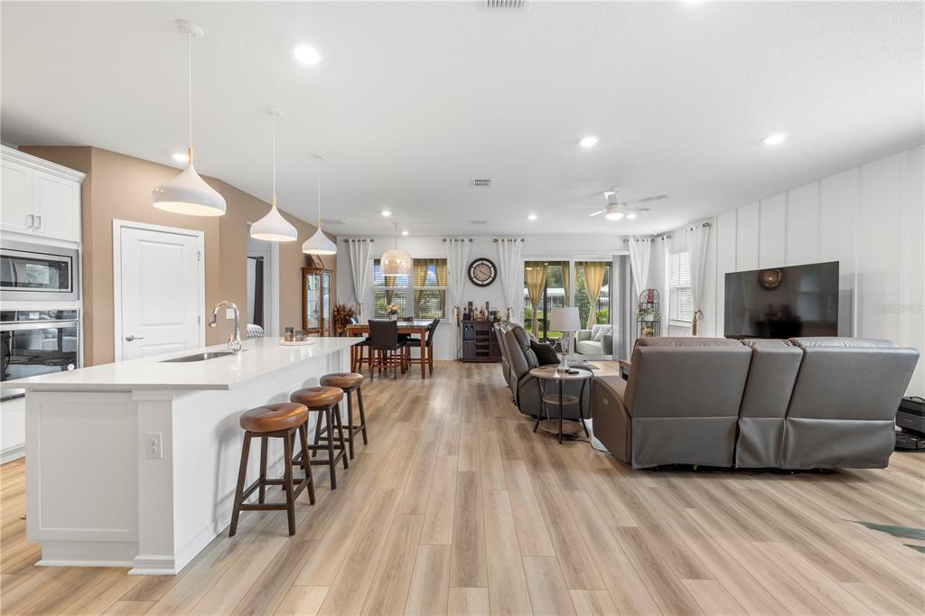 An open-concept kitchen and living area features a white island, wood flooring, and gray furniture — 783 LITTLE CLOUD PLACE, VALRICO, FL
