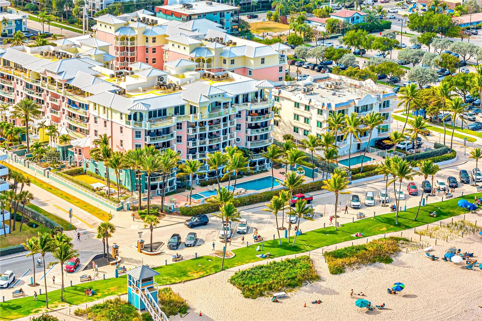 An aerial view shows a multi-story resort complex with pools adjacent to a sandy beach — 2051 SE 3rd St # 407, Deerfield Beach FL 33441, DEERFIELD BEACH, FL