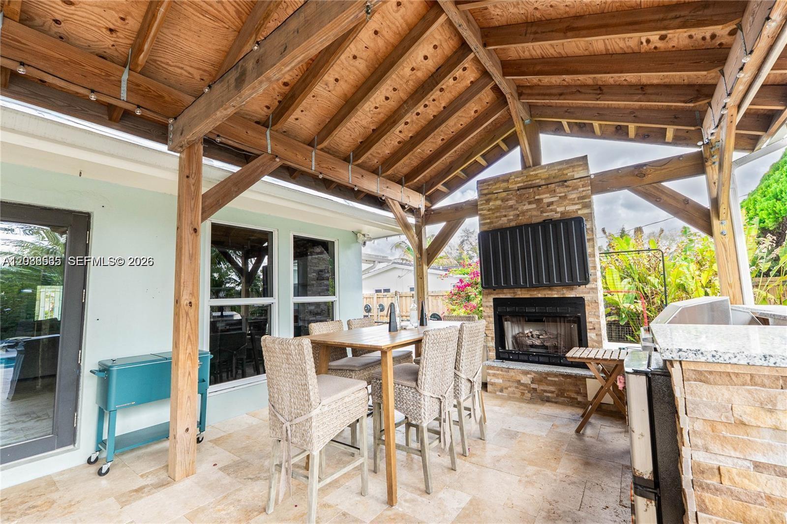 A backyard features a swimming pool with a rock waterfall, stone pavers, and palm trees — 1304 N 40th Ave, Hollywood FL 33021, HOLLYWOOD, FL