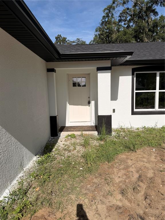 The exterior of a house features a white front door, stucco walls, and black trim — 851 SE 28TH STREET, OCALA, FL