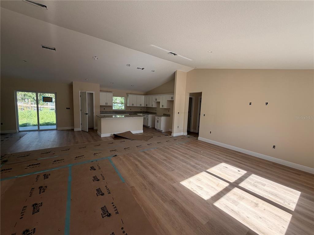 An open-concept living area features light wood flooring, white kitchen cabinetry, and vaulted ceilings — 851 SE 28TH STREET, OCALA, FL