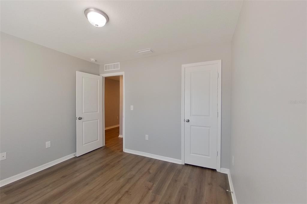 An empty room with light gray walls, wood-look flooring, and two white interior doors — 9810 N SANTEE TERRACE, DUNNELLON, FL