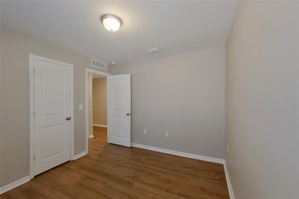 An empty room with light-colored walls, wood-look flooring, and two white interior doors — 9810 N SANTEE TERRACE, DUNNELLON, FL