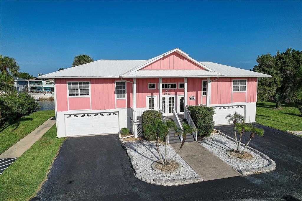 A pink, elevated single-story house with a white metal roof and a two-car garage — 3263 SHOAL LINE BOULEVARD, HERNANDO BEACH, FL