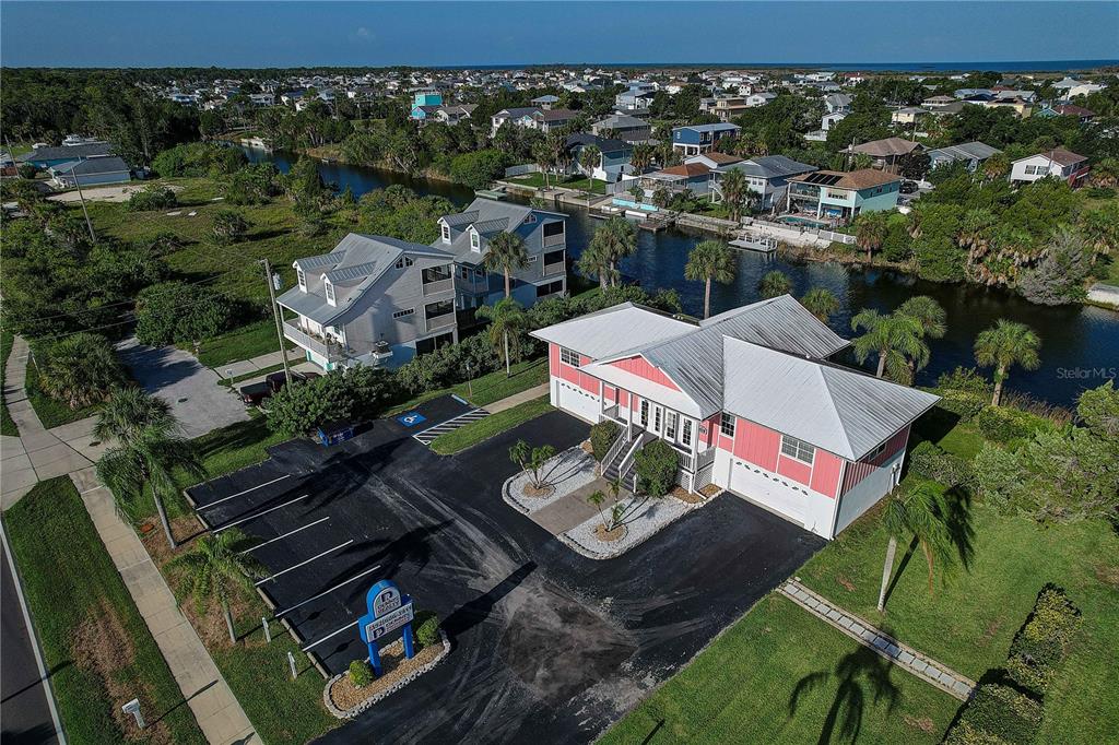 An aerial view shows a pink building with a parking lot and a nearby canal — 3263 SHOAL LINE BOULEVARD, HERNANDO BEACH, FL