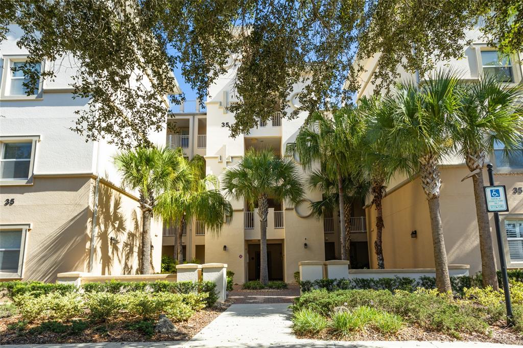A multi-story apartment building exterior features light-colored stucco walls, palm trees, and a walkway — 35 RIVERVIEW BEND S UNIT 1845, PALM COAST, FL