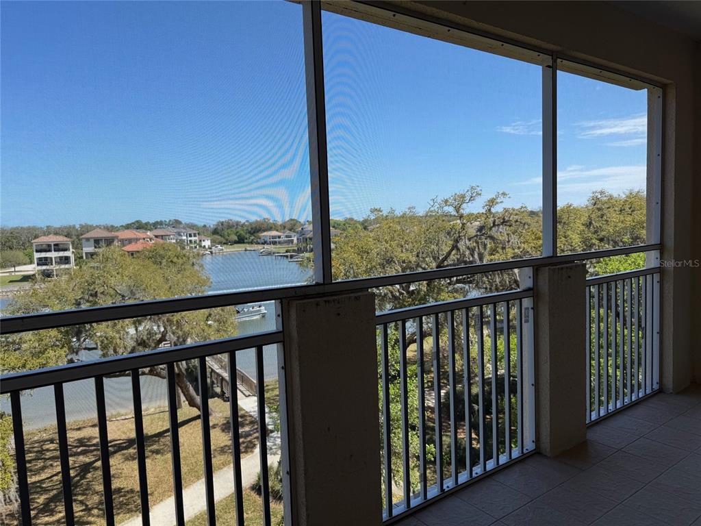 A screened-in balcony overlooks a canal with houses and trees in the distance — 35 RIVERVIEW BEND S UNIT 1845, PALM COAST, FL