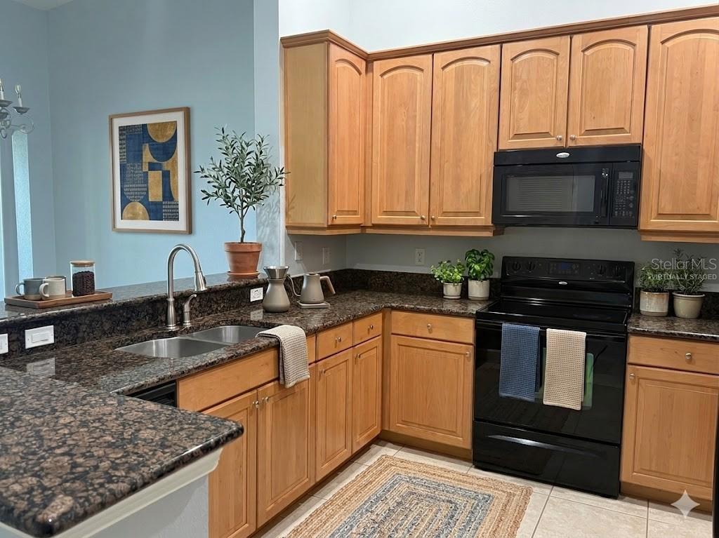 A kitchen features wood cabinets, dark granite countertops, and black appliances — 35 RIVERVIEW BEND S UNIT 1845, PALM COAST, FL