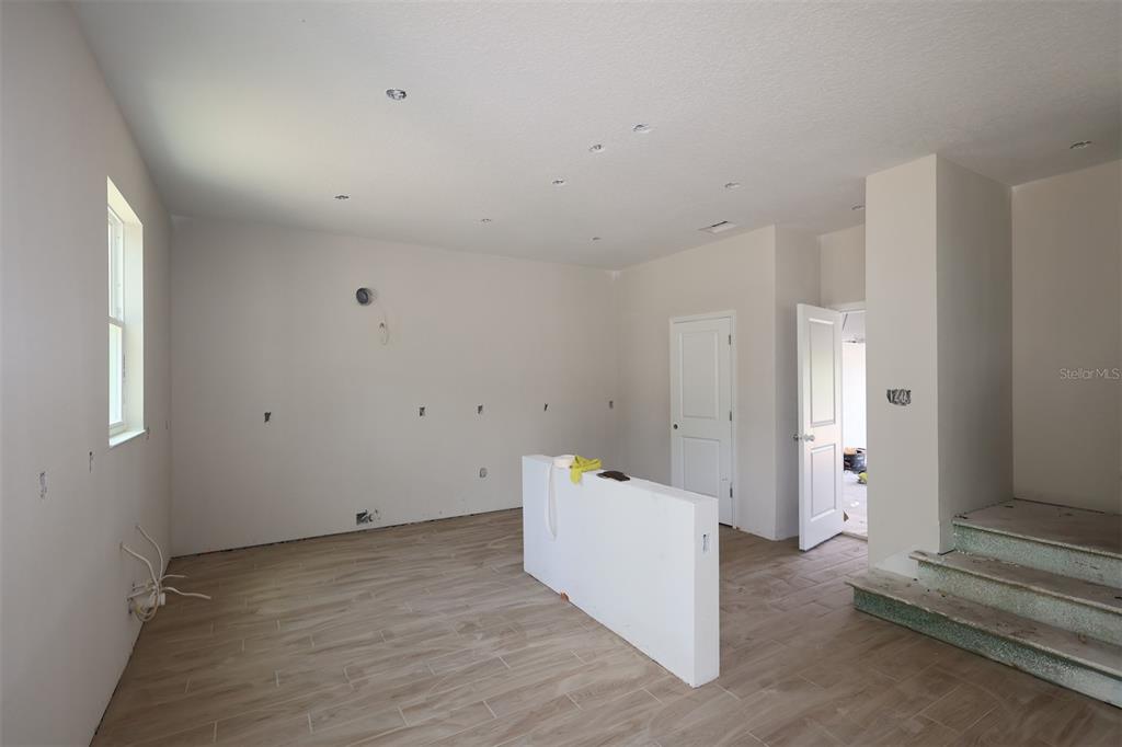 A kitchen with white cabinets, stainless steel appliances, a center island, and unfinished stairs — 6729 YELLOW WARBLER BEND, ST CLOUD, FL