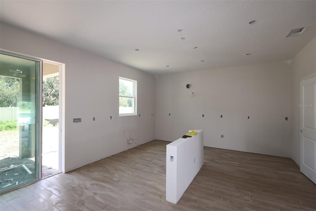 A kitchen with white cabinets, a center island, and a sliding door to the backyard — 6729 YELLOW WARBLER BEND, ST CLOUD, FL