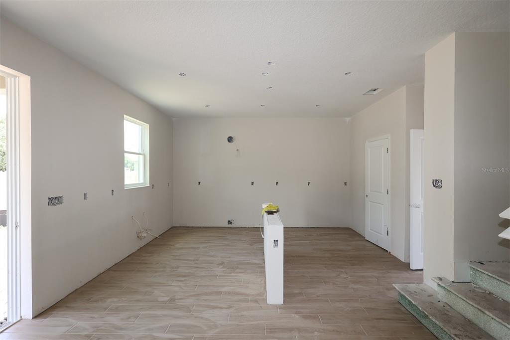 An unfinished room with light walls, a window, and a staircase railing — 6729 YELLOW WARBLER BEND, ST CLOUD, FL