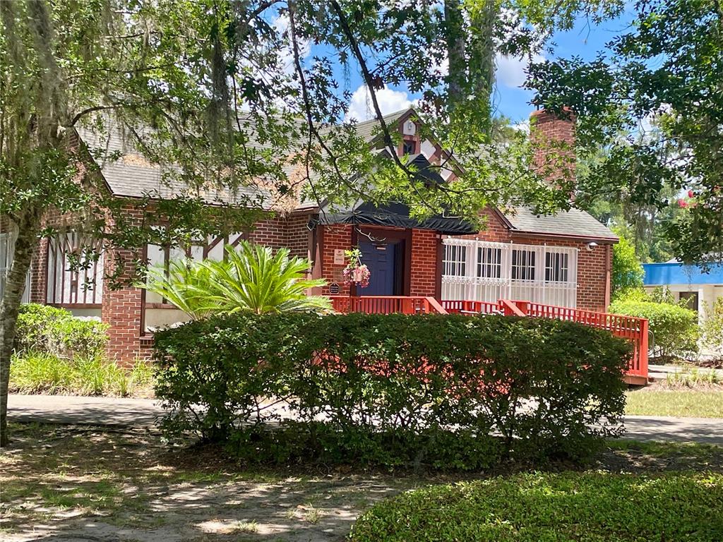 A red brick house with a front porch, black awning, and mature landscaping — 914 NW 13TH STREET, GAINESVILLE, FL