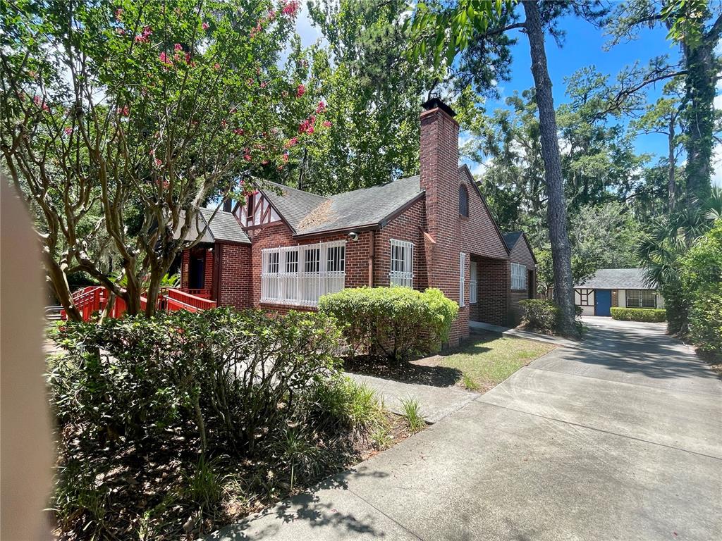 A brick house with a chimney and a red ramp sits beside a concrete driveway — 914 NW 13TH STREET, GAINESVILLE, FL