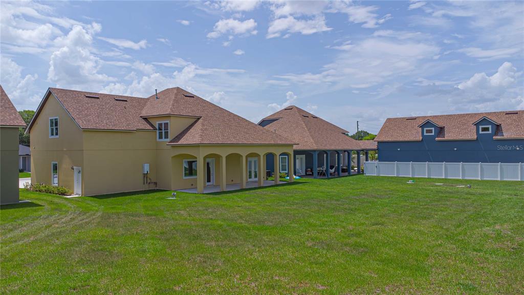 The rear exterior of two suburban houses features covered patios and a shared grassy yard — 1919 SIPES AVENUE, SANFORD, FL