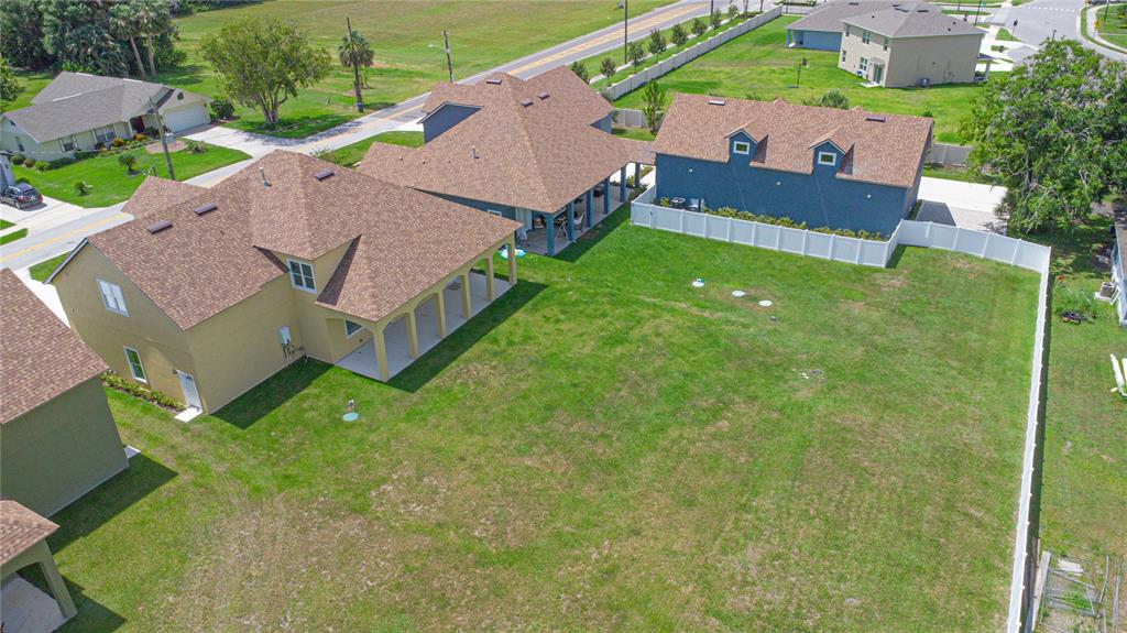 An aerial view shows several suburban houses with brown roofs and a large fenced backyard — 1919 SIPES AVENUE, SANFORD, FL