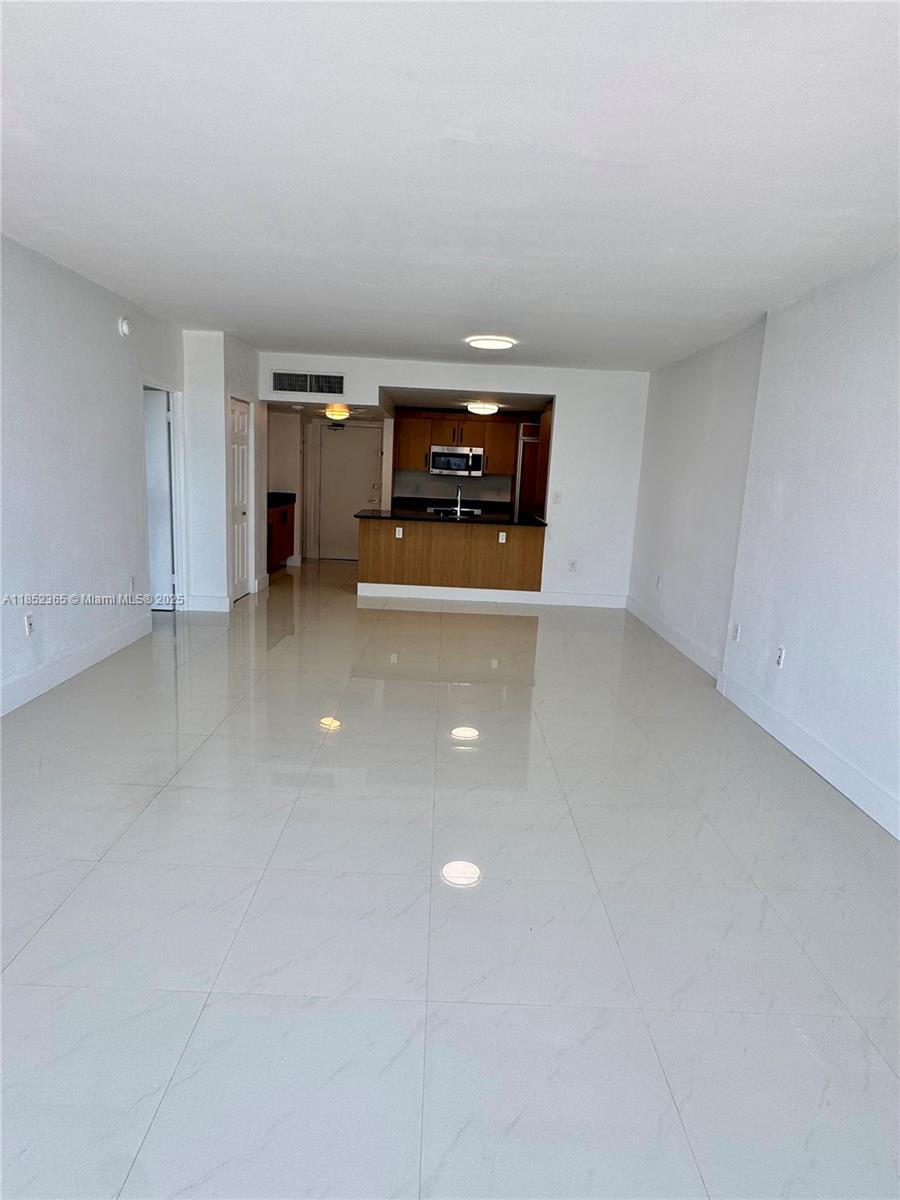 An open-concept living area features white tile flooring and a kitchen with wooden cabinets — 10275 Collins Ave # 316, Bal Harbour FL 33154, BAL HARBOUR, FL