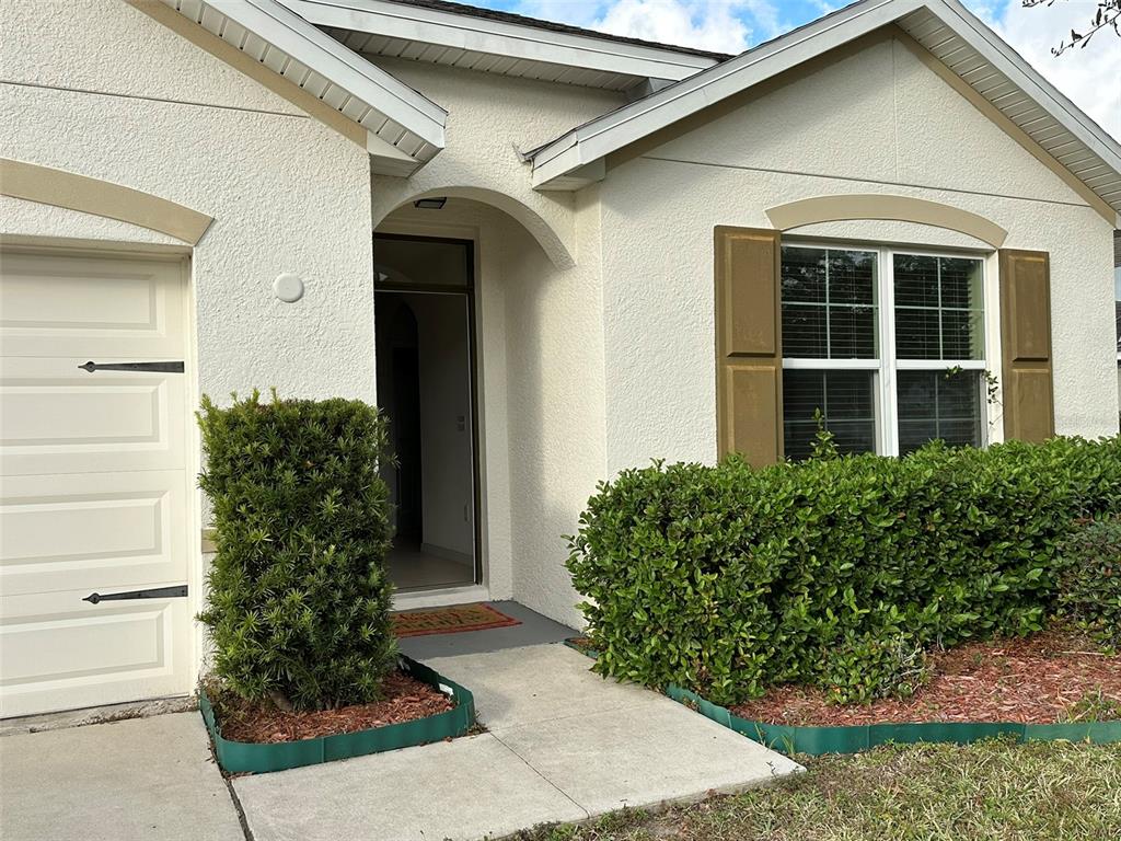 The exterior of a house features a garage, a front entrance, and landscaped bushes — 13515 HAVERHILL DRIVE, SPRING HILL, FL