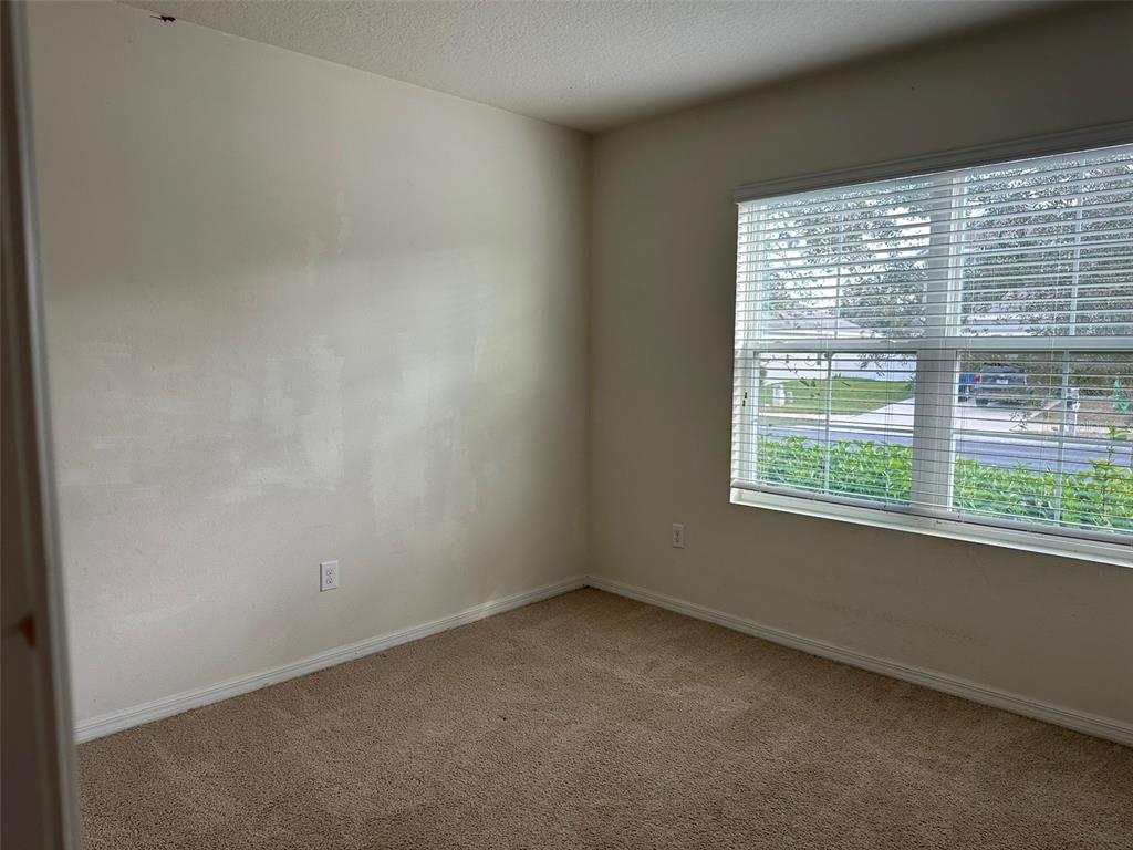 An empty bedroom with beige carpet, off-white walls, and a window with white blinds — 13515 HAVERHILL DRIVE, SPRING HILL, FL