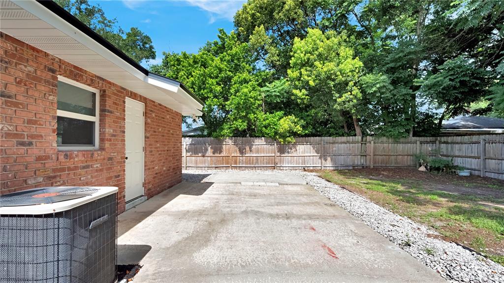 A brick house exterior features a concrete patio, an HVAC unit, and a wooden fence — 1179 FOREST HILLS ROAD, ALTAMONTE SPRINGS, FL