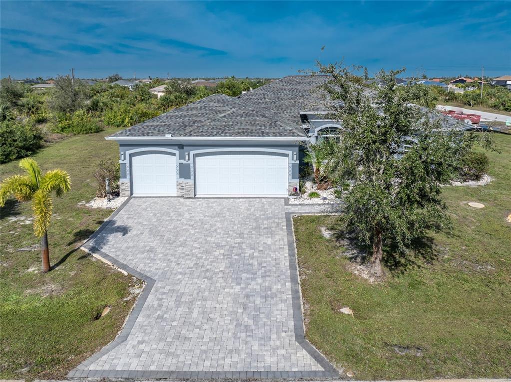 An aerial view of a single-story house with a three-car garage and paved driveway — 14344 AMESTOY AVENUE, PORT CHARLOTTE, FL