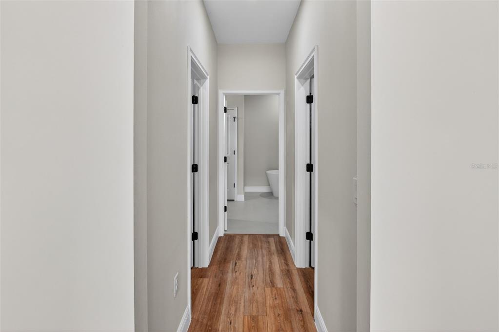 A hallway with wood-look flooring leads to a bathroom featuring a white freestanding tub — 8135 N TINY LILY DRIVE, CITRUS SPRINGS, FL