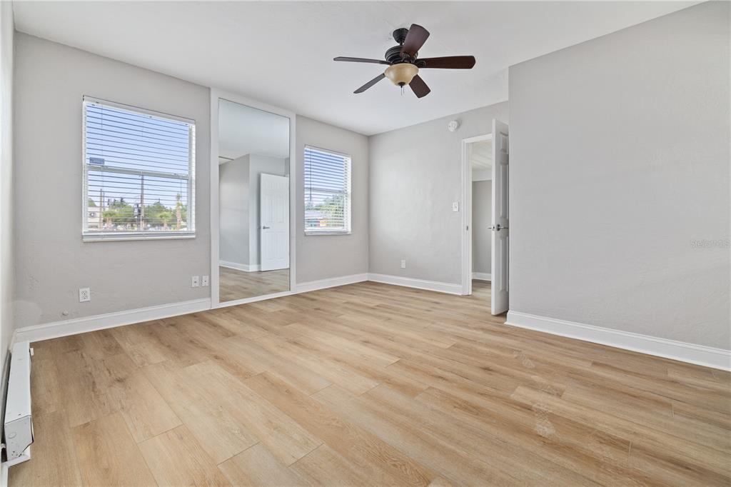 An empty bedroom features light wood-look flooring, gray walls, a ceiling fan, and mirrored closet doors — 917 30TH AVENUE N UNIT 1, ST PETERSBURG, FL