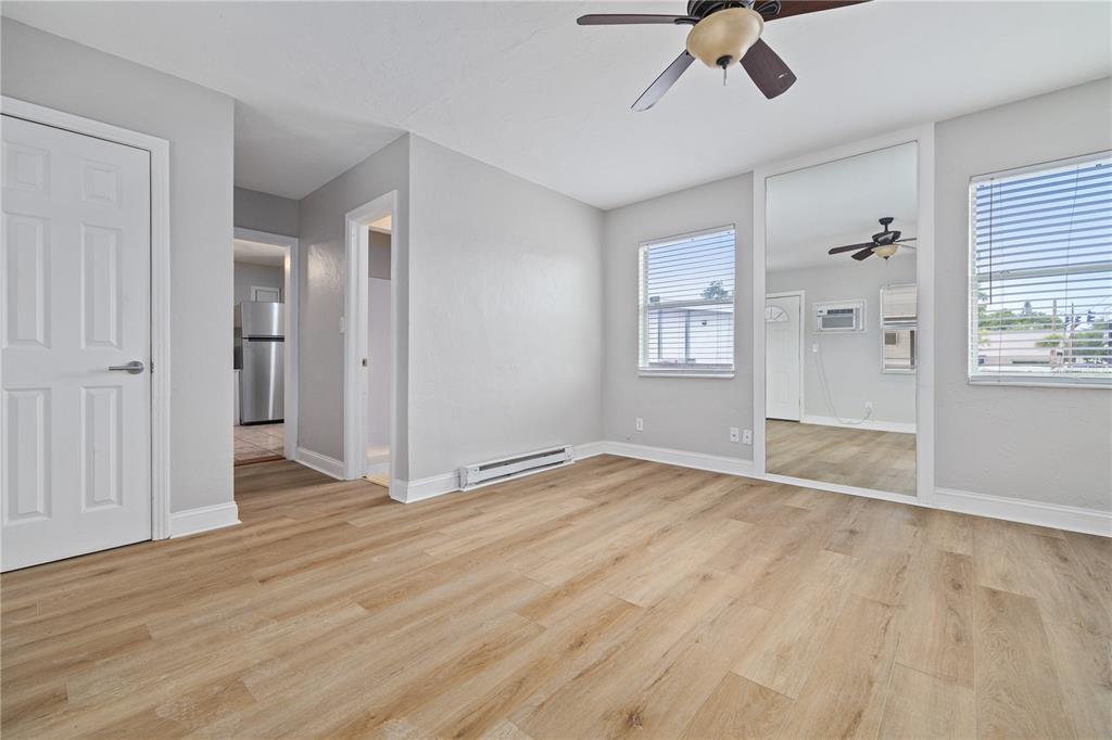 A bedroom with light gray walls, wood-look flooring, a ceiling fan, and mirrored closet doors — 917 30TH AVENUE N UNIT 1, ST PETERSBURG, FL