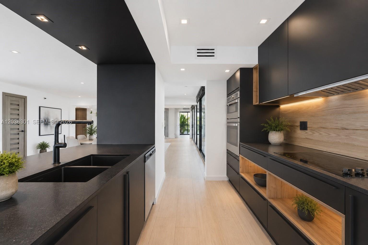 A modern kitchen features black cabinetry, light wood accents, and a central island with a sink — 801 N Venetian Dr # 308, Miami FL 33139, MIAMI, FL