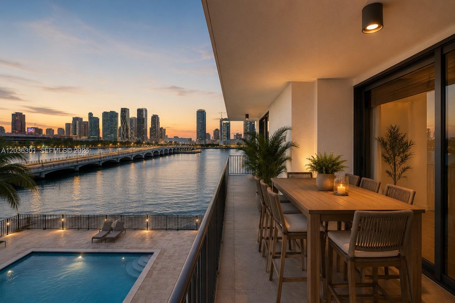 A balcony with a dining set overlooks a swimming pool, a bridge, and a city skyline — 801 N Venetian Dr # 308, Miami FL 33139, MIAMI, FL