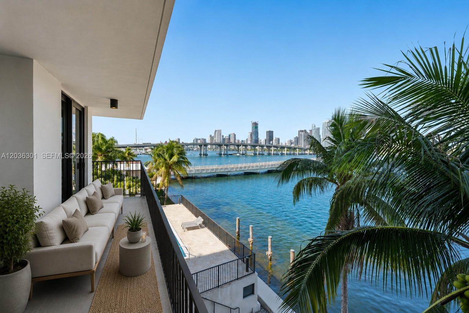 A balcony with a sofa overlooks a waterfront view of a city skyline and bridge — 801 N Venetian Dr # 308, Miami FL 33139, MIAMI, FL