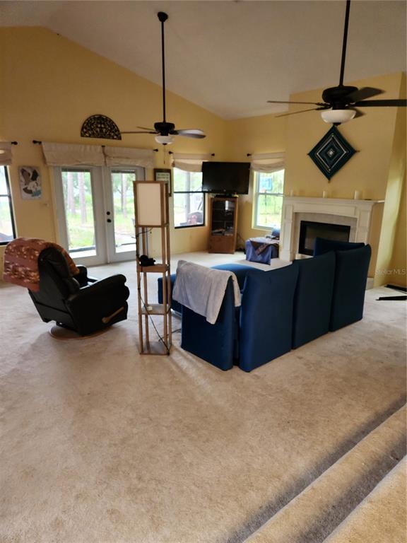 A room with carpeted flooring looks out through a sliding glass door onto a lake — 235 ASHLEY LAKE DRIVE, MELROSE, FL