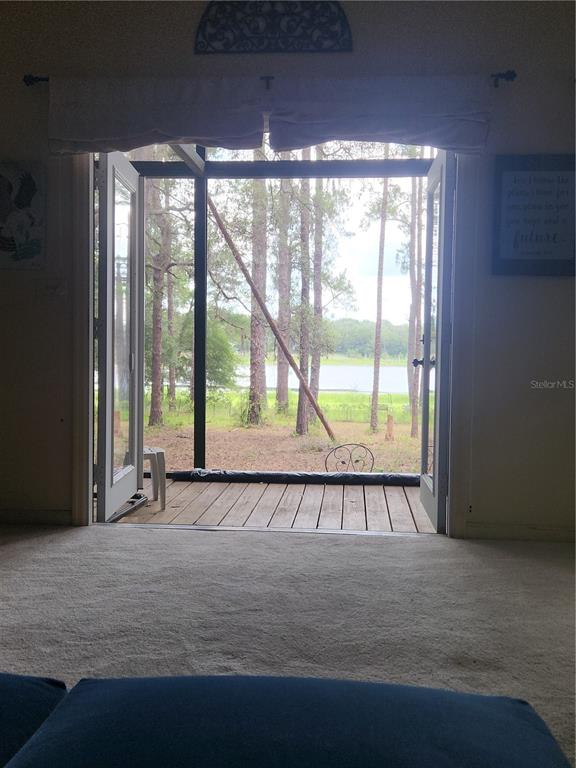 A spacious living room features vaulted ceilings, a blue sectional sofa, and a hanging hammock — 235 ASHLEY LAKE DRIVE, MELROSE, FL