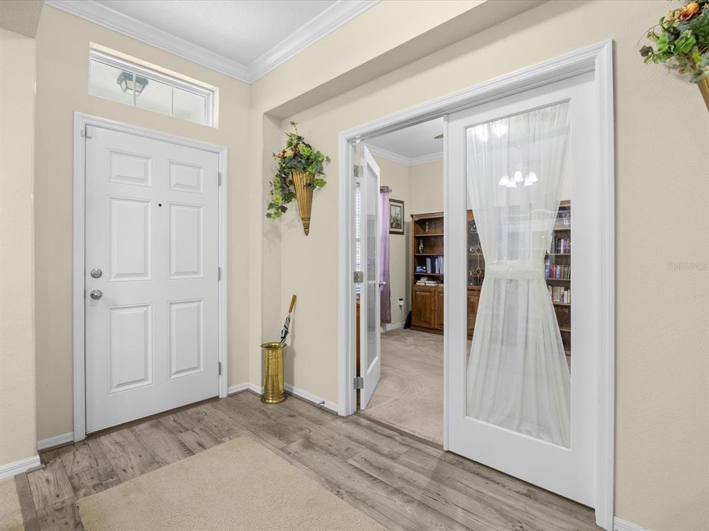 An entryway features a white front door, wood-look flooring, and glass-paneled double doors to a room — 307 GLADESDALE STREET, HAINES CITY, FL