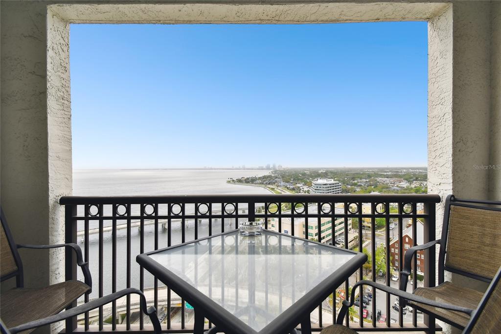 A balcony with a glass-topped table and two chairs overlooks a bay and city skyline — 345 BAYSHORE BOULEVARD UNIT P9, TAMPA, FL