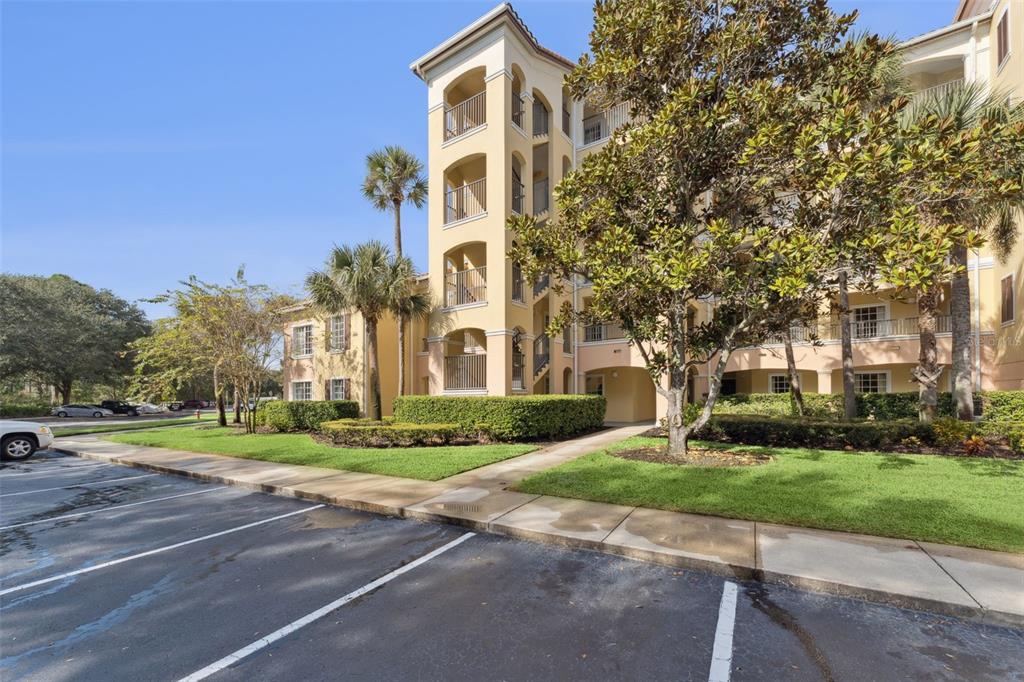 A multi-story apartment building with a parking lot, landscaping, and palm trees — 8801 WORLDQUEST BOULEVARD UNIT 4108, ORLANDO, FL