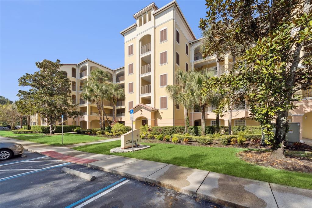 A multi-story yellow apartment building with balconies and a parking lot in the foreground — 8801 WORLDQUEST BOULEVARD UNIT 4108, ORLANDO, FL