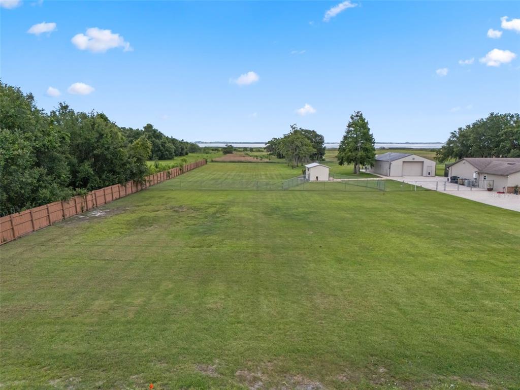 A large, grassy backyard features a wooden fence, a small shed, and a detached garage — LAKE TOHOPEKALIGA BOULEVARD, KISSIMMEE, FL