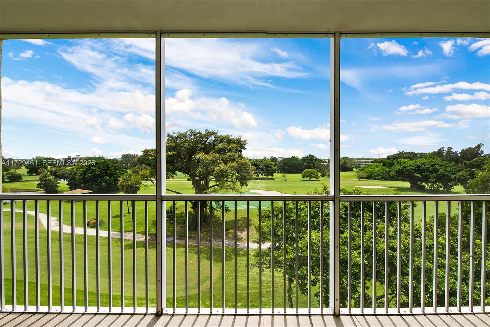 A screened-in balcony overlooks a green golf course under a blue sky — 3050 N Palm Aire Dr # 501, Pompano Beach FL 33069, POMPANO BEACH, FL