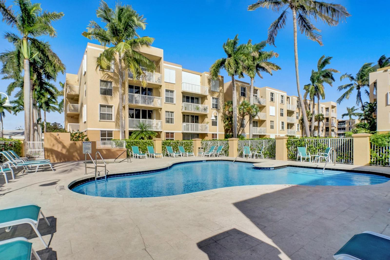 A swimming pool sits in front of a multi-story apartment building with palm trees — 1350 SE 3rd Avenue # 406, Dania Beach FL 33004, DANIA BEACH, FL